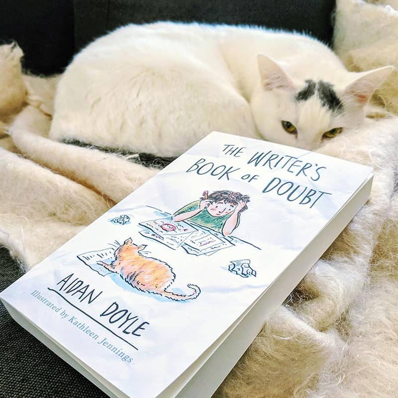 Cat sitting next to The Writer's Book of Doubt by Aidan Doyle