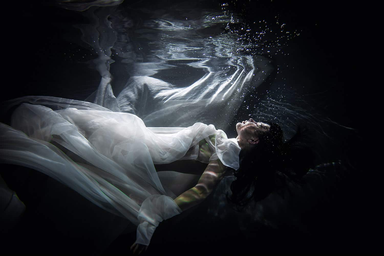 Mysterious woman in white floating underwater