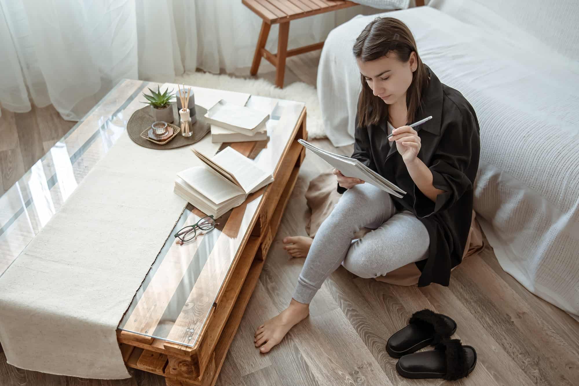 A girl with a notebook and books studies at home in a cozy atmosphere.